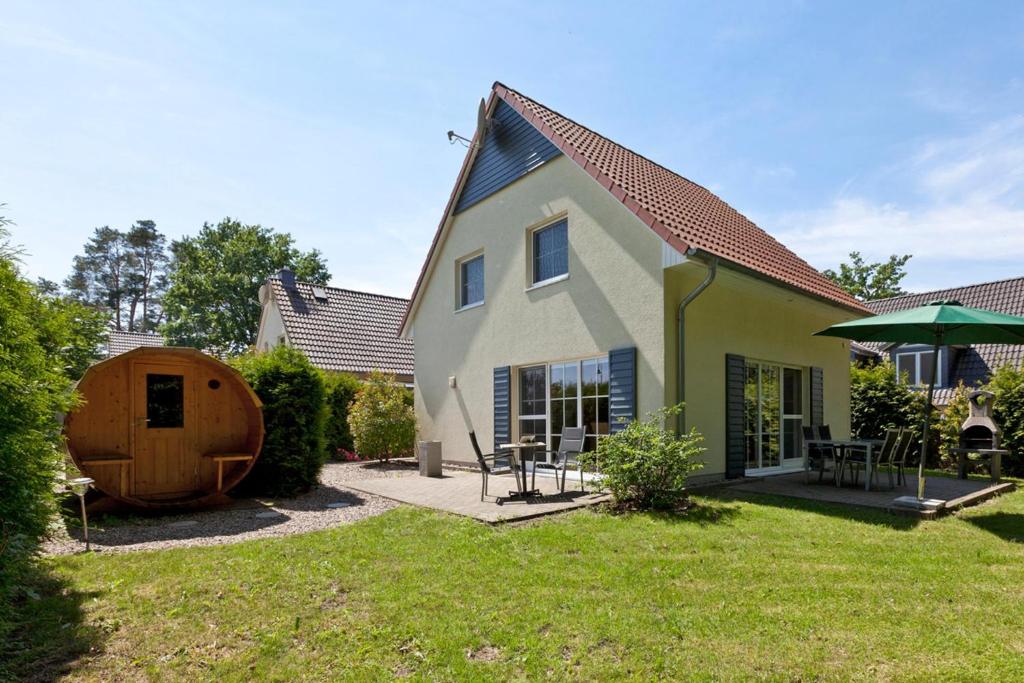 a house with a yard with a wooden barrel at Ferienhaus Buche im Land Fleesensee in Göhren-Lebbin