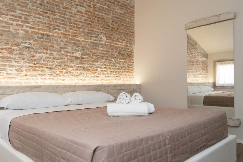 a bedroom with a brick wall and a bed with two towels at Chioggia Apartment in Chioggia