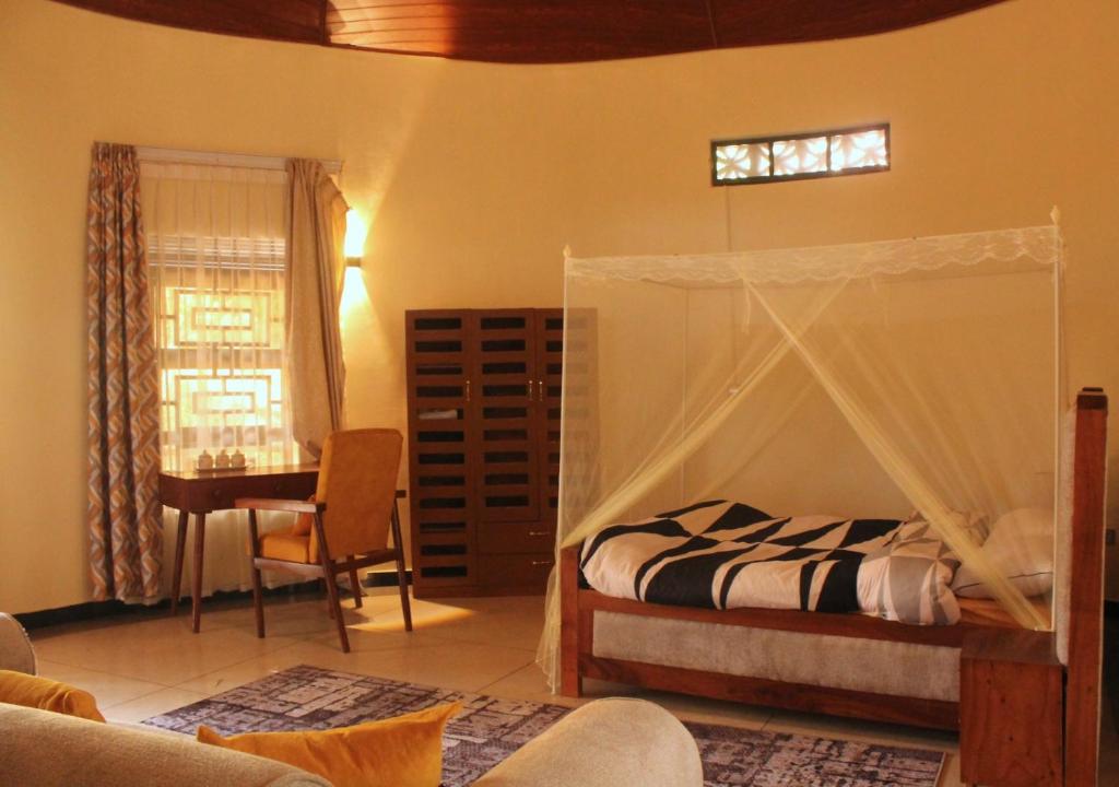 a bedroom with a canopy bed and a desk at Gejja Cottage in Lwanga