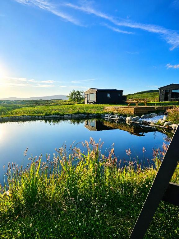 a view of a pond with a house in the background at Wild Hideaways Luxury Lodges and Eco Spa in Bantry