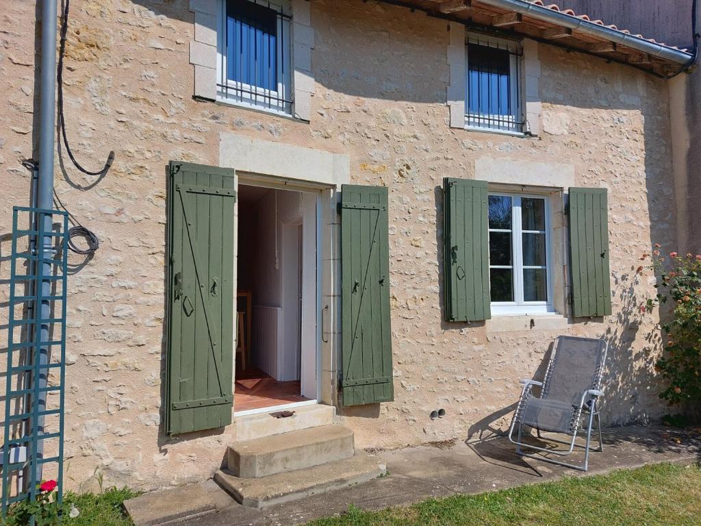 a building with green shutters and a chair outside at Gite des Anglais in Marnay
