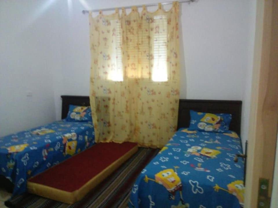a bedroom with two twin beds and a window at Dar Si Lamin 2 in Kelibia