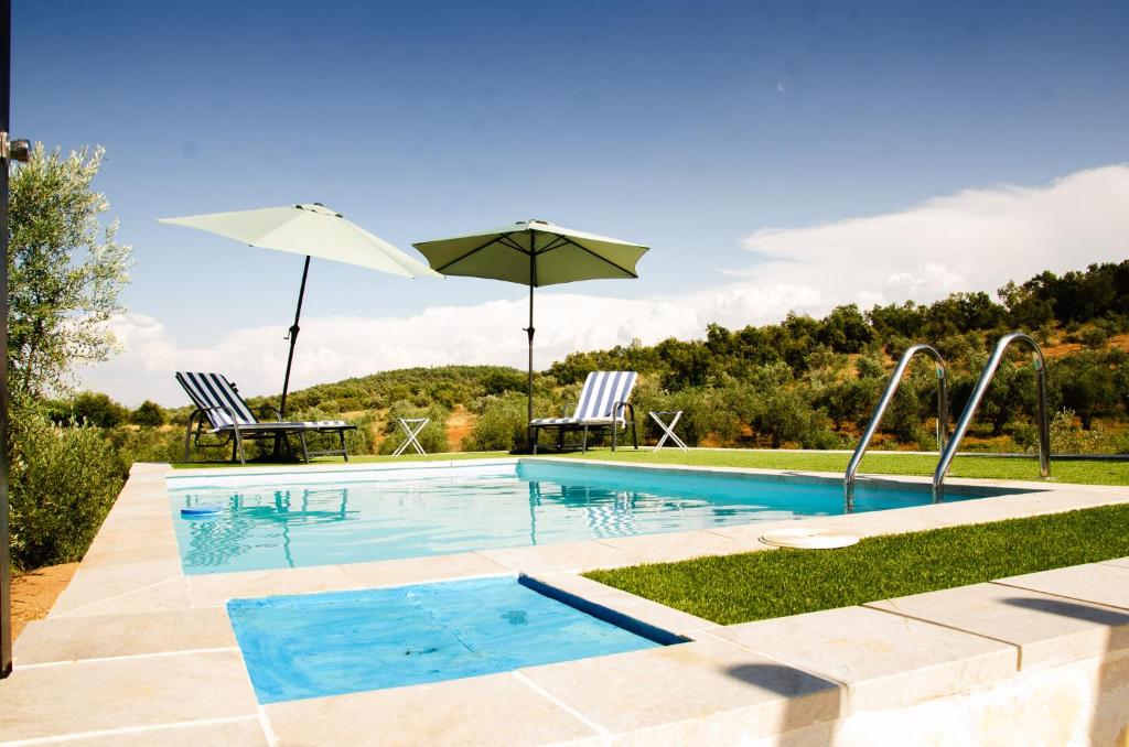 a swimming pool with two chairs and an umbrella at O Rossio in Esperança