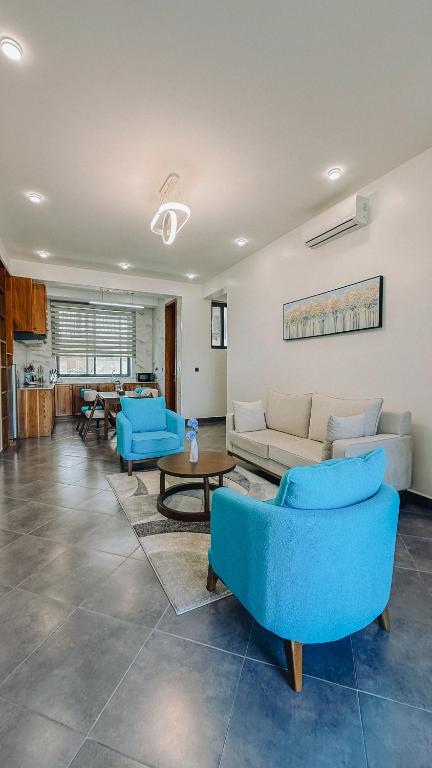 a living room with blue chairs and a couch at Zabibu Collection in Arusha