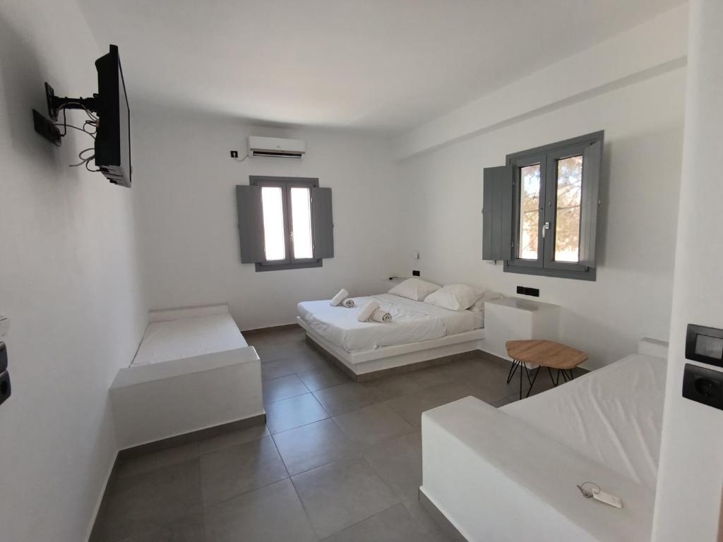 a white living room with two white couches and two windows at Perissa Economy Rooms in Santorini
