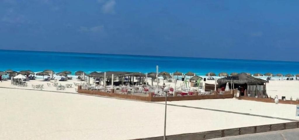 a beach with chairs and umbrellas and the ocean at Coastal Comforts at Casabianca in Dawwār Muḩammad Abū Shanab