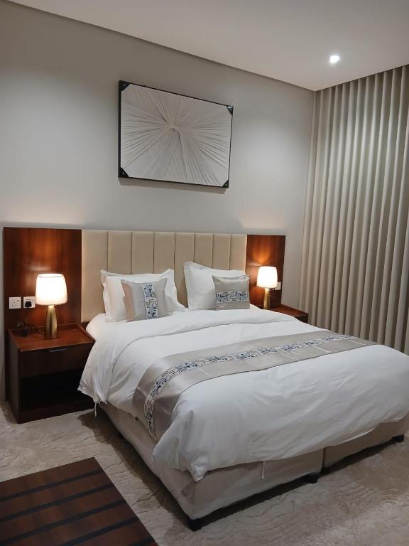 a bedroom with a large white bed with two lamps at علي ريزيدنس Ali Residence in Khamis Mushayt