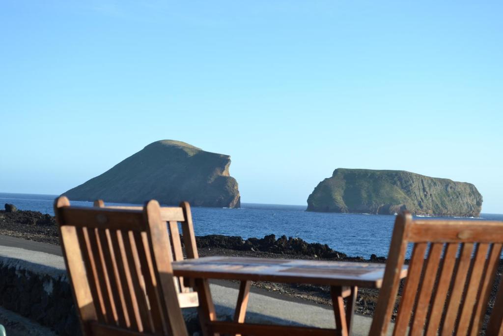dwa krzesła siedzące na plaży z oceanem w obiekcie Casa Doce Mar w mieście Feteira