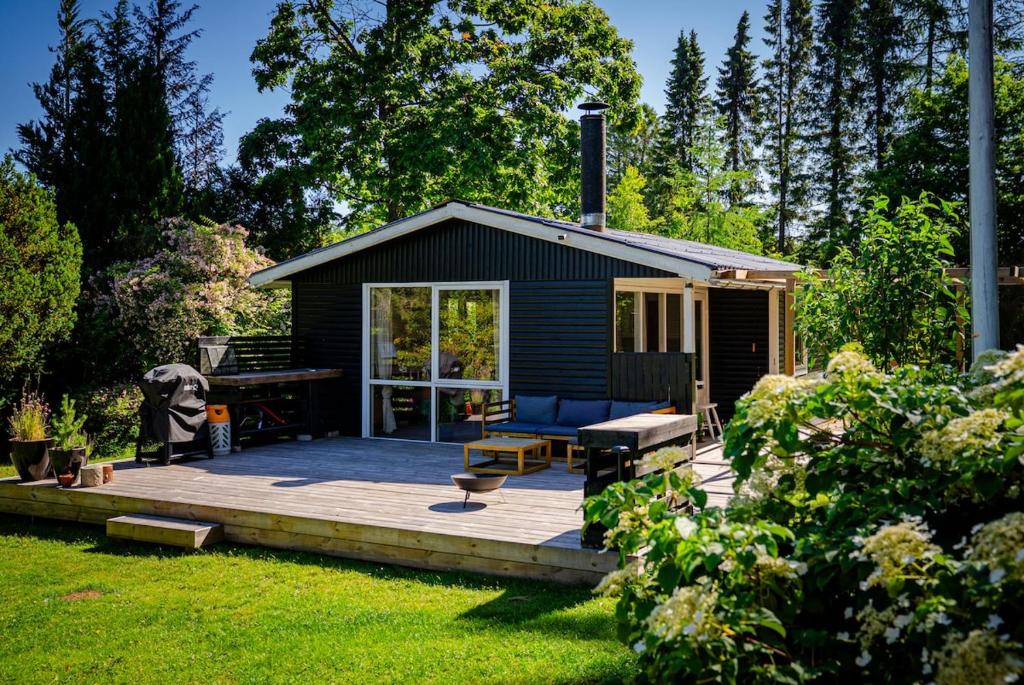 a small cabin with a wooden deck in the yard at Holiday house close to nature in Glesborg