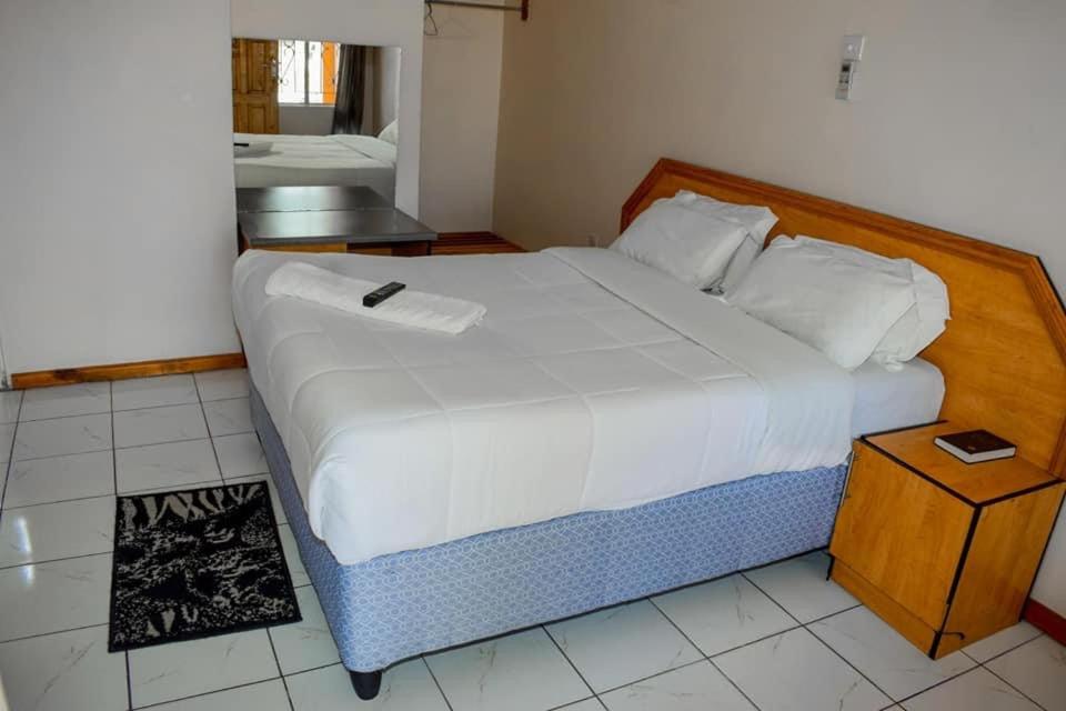 a bedroom with a large bed with a wooden headboard at Mana Nest Lodge in Choma