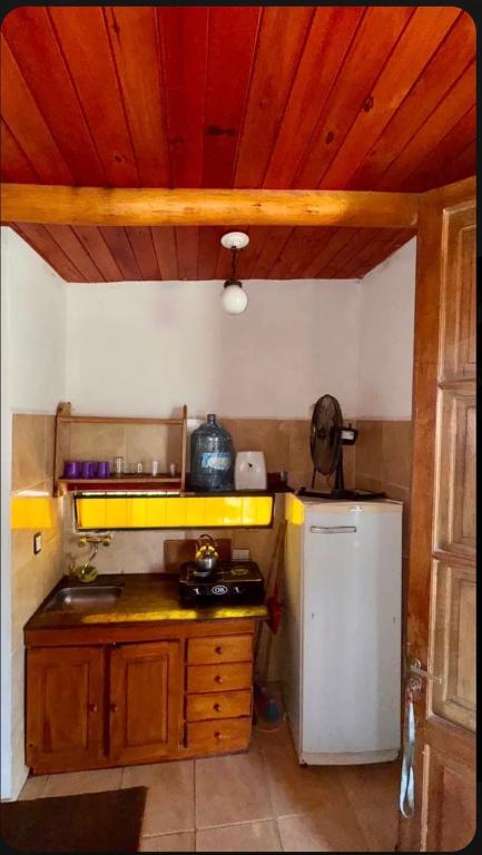 a kitchen with a white refrigerator and a wooden ceiling at Cabaña Camping Cabalango in Cavalango