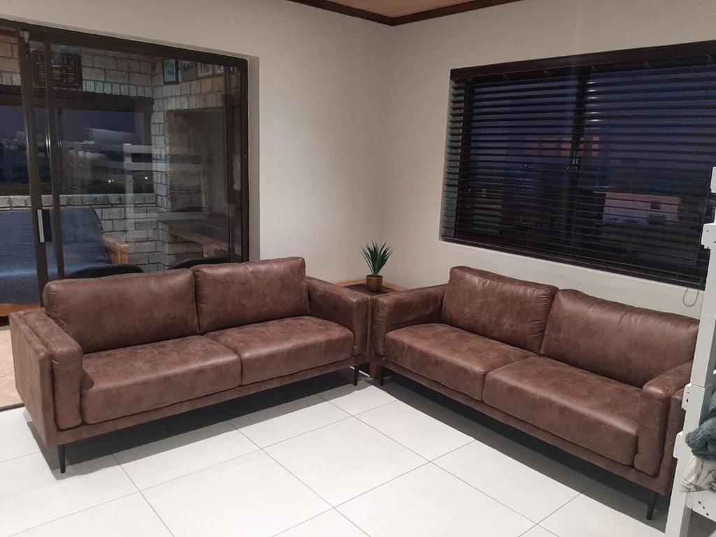 a living room with two brown couches and a window at Klein Plasie - St Helena Bay in Stompneusbaai