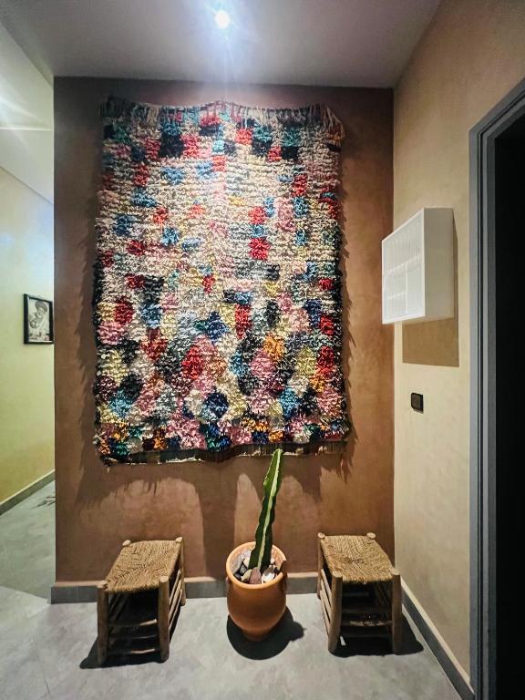 a large tapestry hanging on a wall with two stools at Zakar Apartments & Terrace 2 in Mirleft