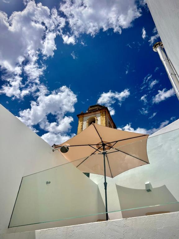 a tan umbrella in front of a building with a clock tower at Villa Nooma Elvas in Elvas
