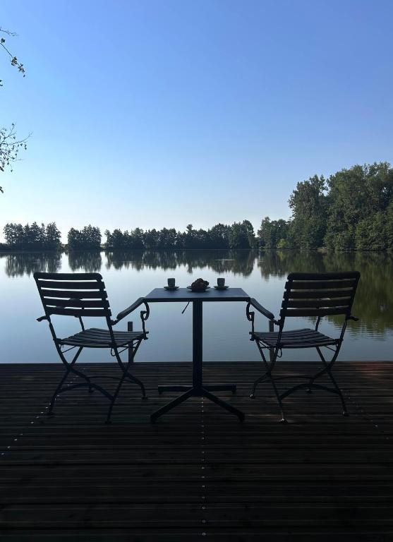 a picnic table with two chairs and a lake at Glamping Hynkov in Příkazy