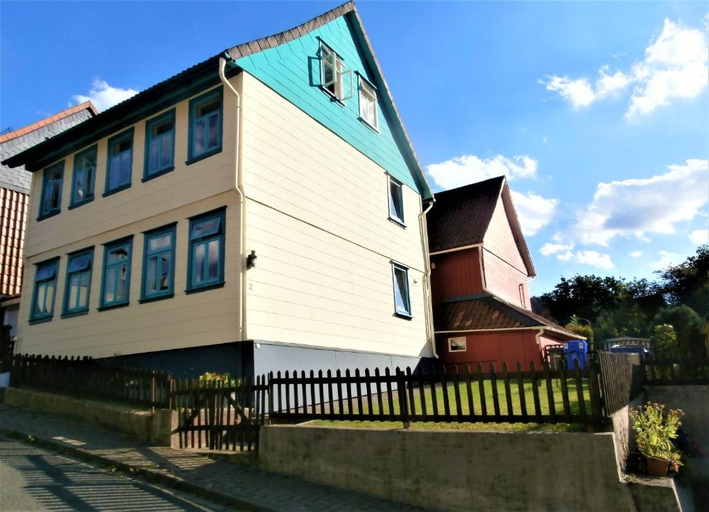 ein weißes Haus mit einem blauen Dach und einem Zaun in der Unterkunft Haus am Bielstein in Lautenthal