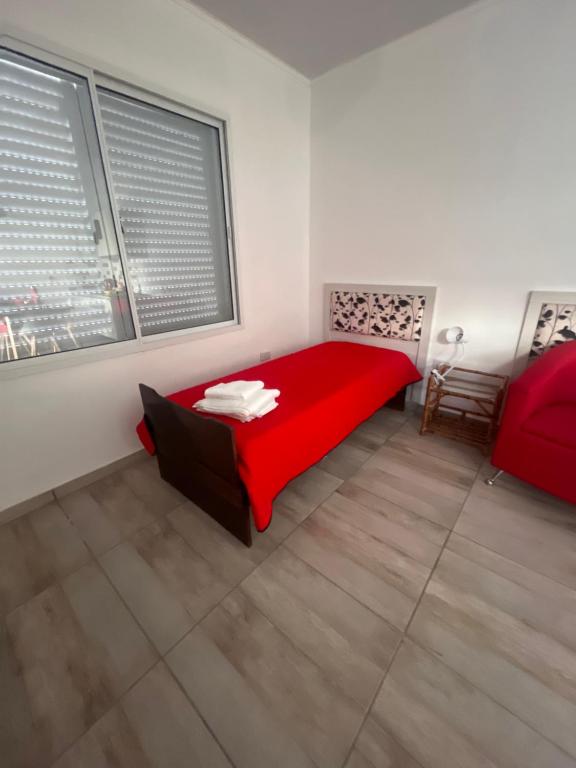 a bedroom with a red bed and two windows at Temporario Martínez in General Pico