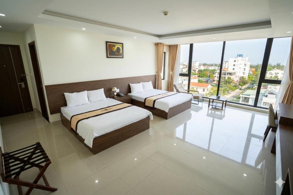 a hotel room with two beds and a balcony at Thăng long II Hotel flc sầm sơn Thanh Hóa in Sầm Sơn