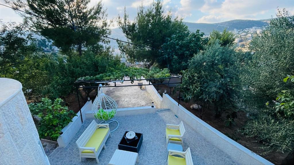 a patio with two chairs and a bird cage on it at Mountain View House- بيت إطلالة الجبل in Ajloun