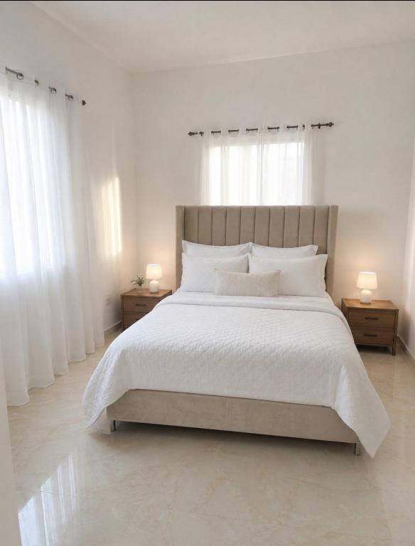 a white bedroom with a large bed with white pillows at Alojamiento en Miches in Miches