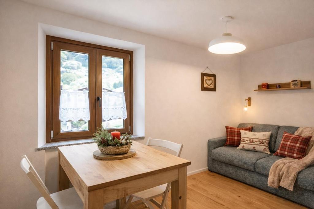 a living room with a table and a couch at Suite Bormio - with WIFI & Netflix in Piatta