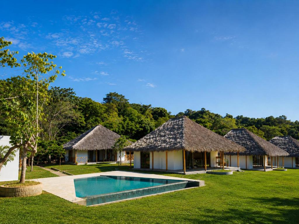 a group of huts with a swimming pool in a yard at ITAMPOLO Suites & Lodges in Nosy Be