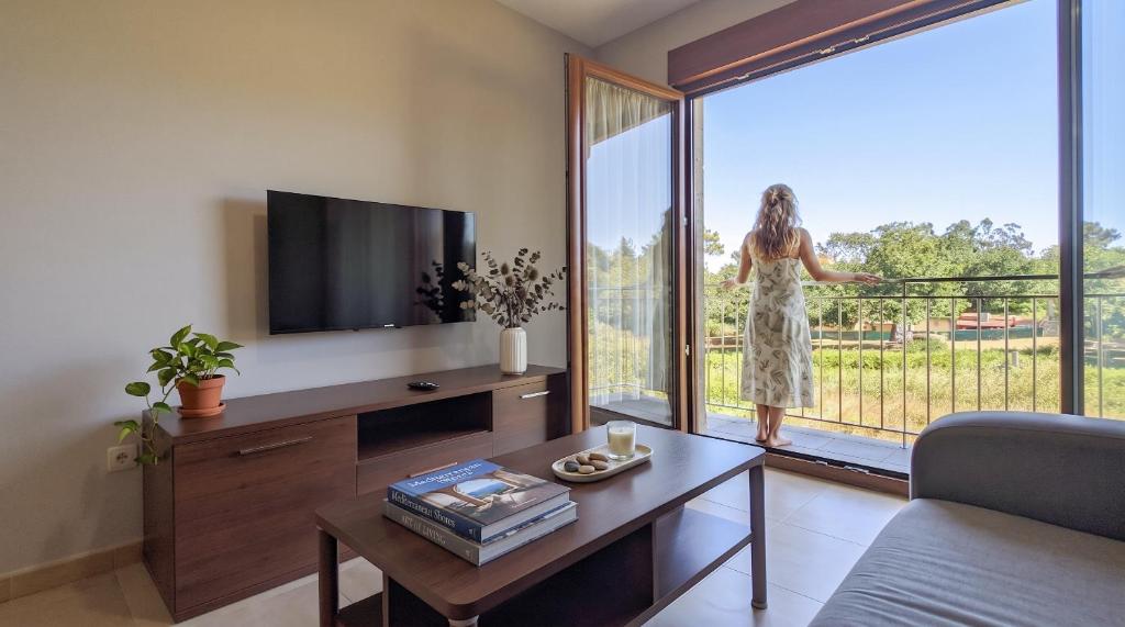 a woman is looking out the window of a living room at Duerming La Rana Sanxenxo in Sanxenxo