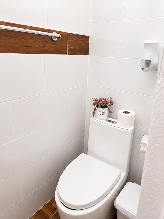 a white bathroom with a toilet with flowers on it at Bon Appetit Hotel & Restaurant Barahona in Santa Cruz de Barahona