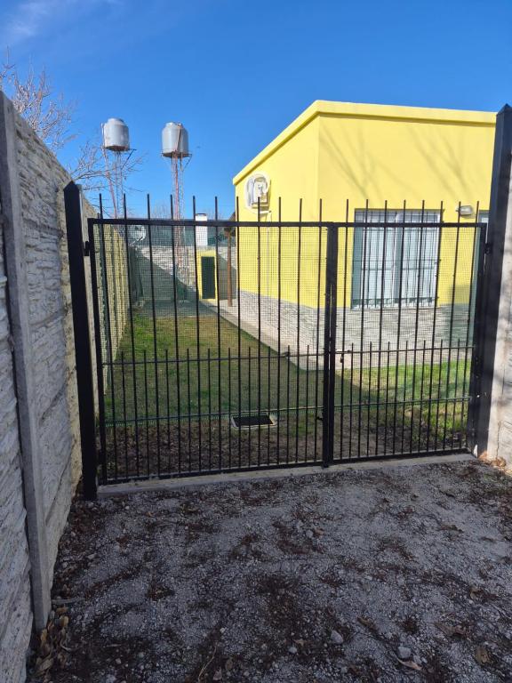 a black gate with a yellow building behind it at Casa Amarilla in Luján