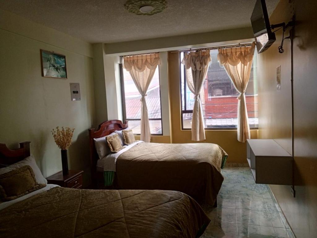 a hotel room with two beds and a window at Hotel Casa Nova in Tulcán