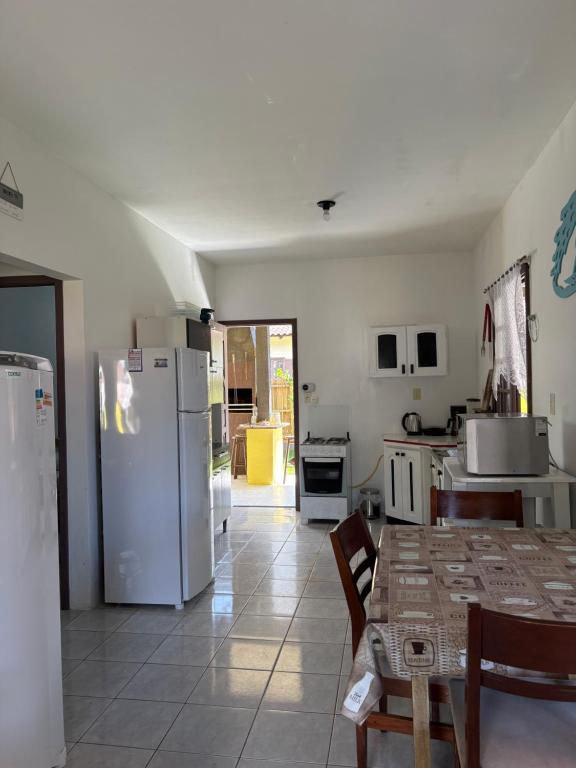 a kitchen with a table and a refrigerator at Você vai sentir em casa in Itapoa