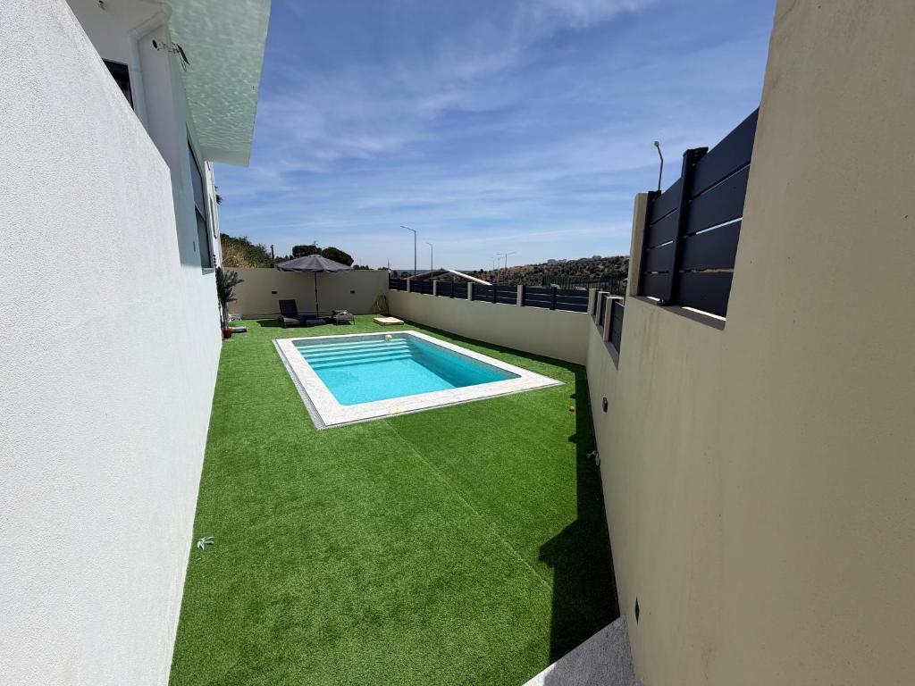 a backyard with a swimming pool and green grass at Vila Grafenola in Montargil