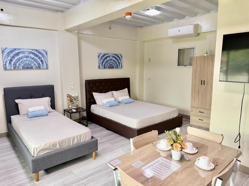 a room with two beds and a table and a tv at MF Suites in Manolo Fortich
