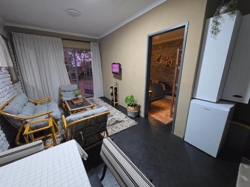 a living room with chairs and a white refrigerator at The Cottage Inn in Modimolle