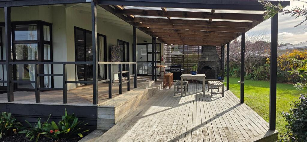 a house with a wooden deck with a table at Point Wells Village Bach in Omaha