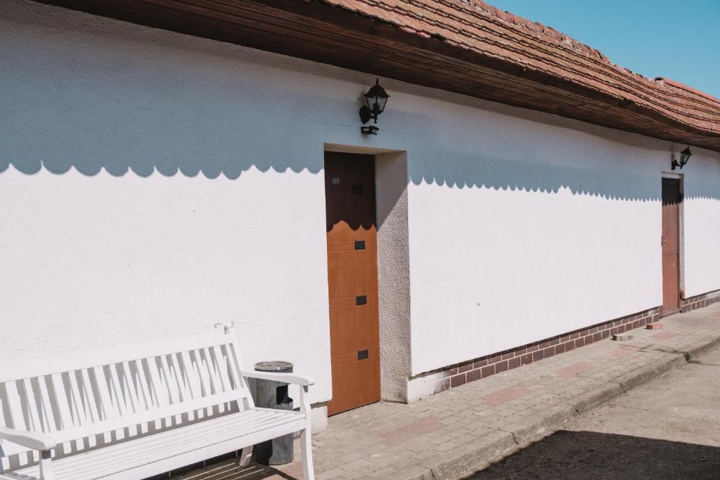 a white building with a wooden door and a bench at Motel Witnica in Witnica