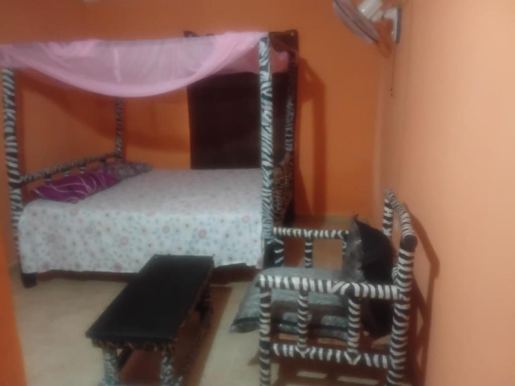 a bedroom with a canopy bed and two chairs at Bububu creek house in Mombasa