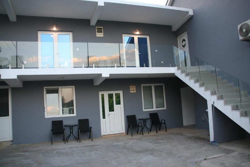 a building with a staircase and chairs in front of it at B&I apartmani in Glavatske Kućice