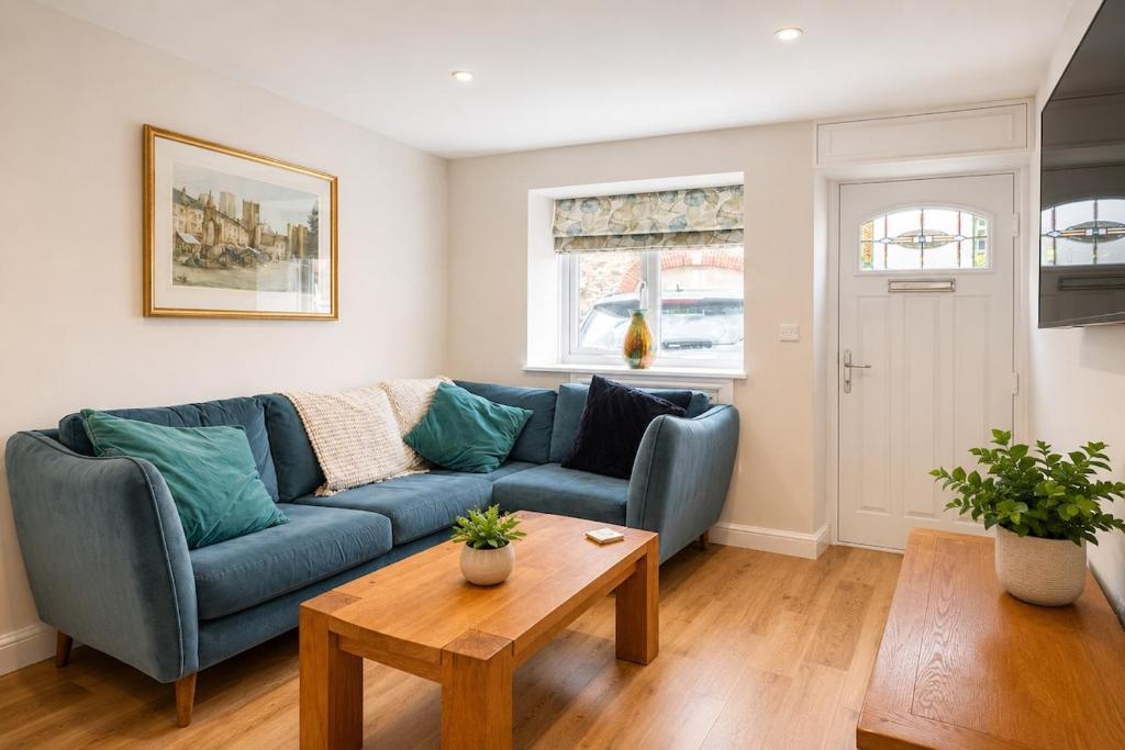 a living room with a blue couch and a table at Appletree Cottage in Wells