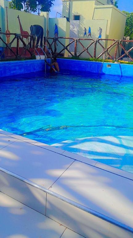 a pool of blue water with people in the background at Maisara lodge in Kilindoni