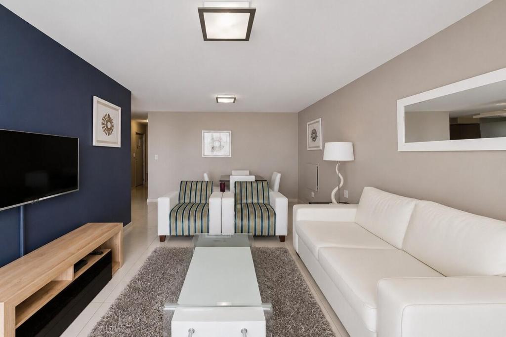 a living room with a white couch and a tv at Modern Ocean View Apartment in Cape Town