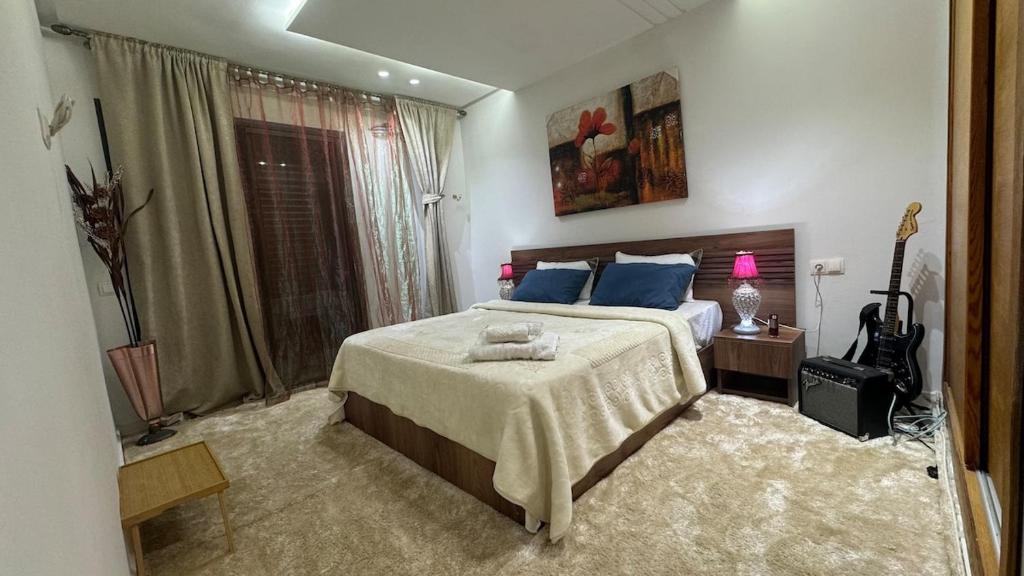 a bedroom with a large bed with blue pillows at Airport's Layover Apartment in Nouaceur