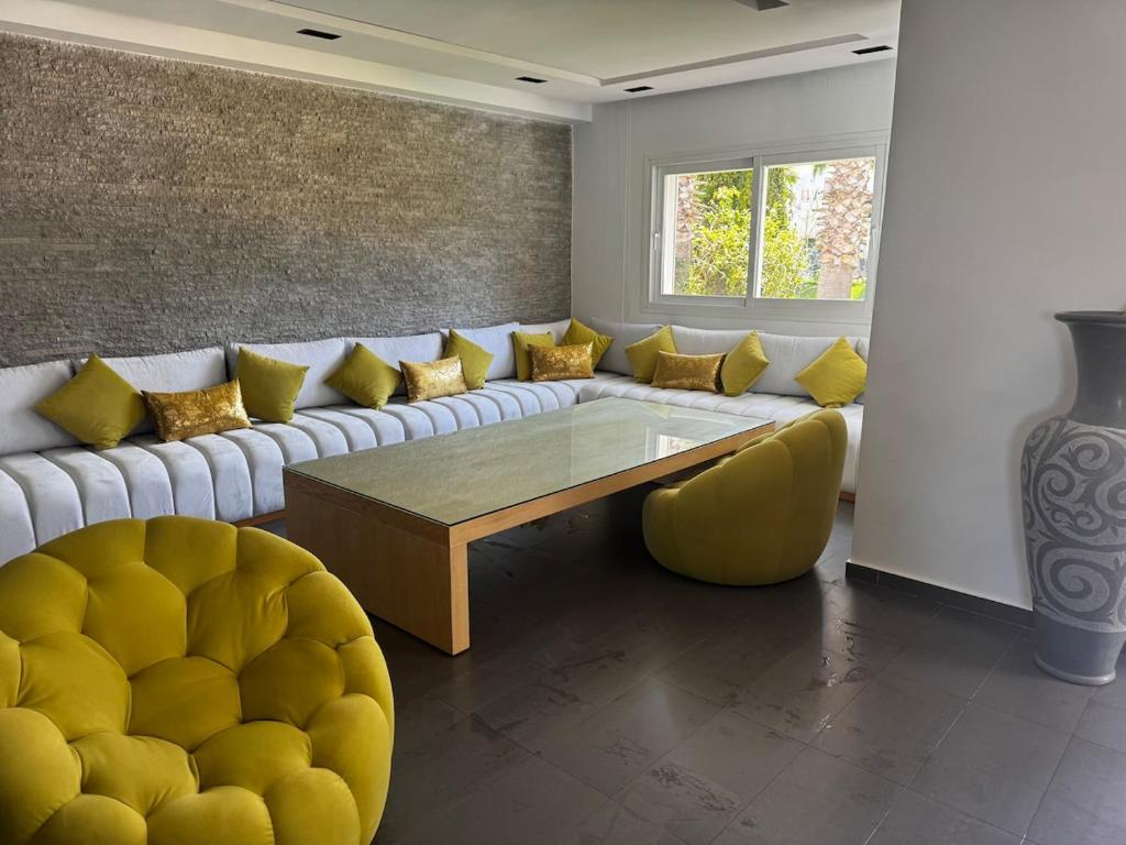 a living room with a couch and a table at Villa Triplex avec piscine proche de la mer in El Harhoura