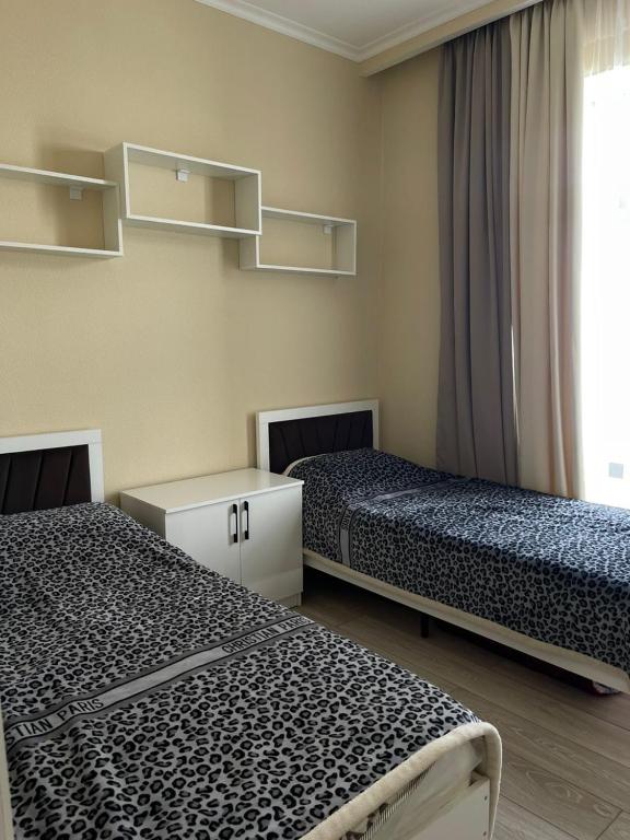 a room with two beds and a window with shelves at Коттедж Атлантис in Balykchy
