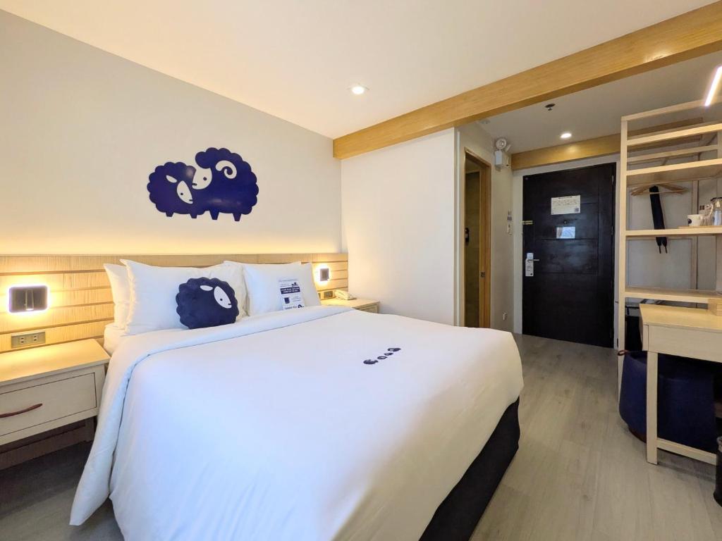 a bedroom with a large white bed and a desk at Kokotel Cebu Capitol in Cebu City