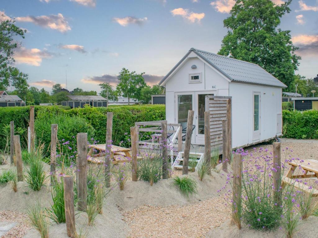 a small white shed with a fence and flowers at Sea Foam in Ellemeet