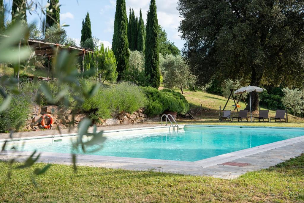 a swimming pool in a yard with an umbrella at Podere Sant'Alessandro in Rapolano Terme