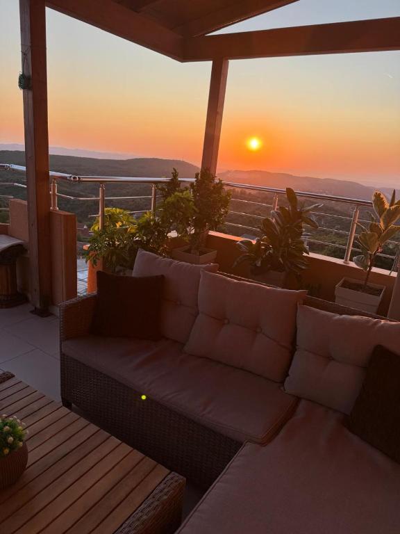 a couch on a balcony with a sunset in the background at Panoramic Krujë Escape BAMI in Krujë