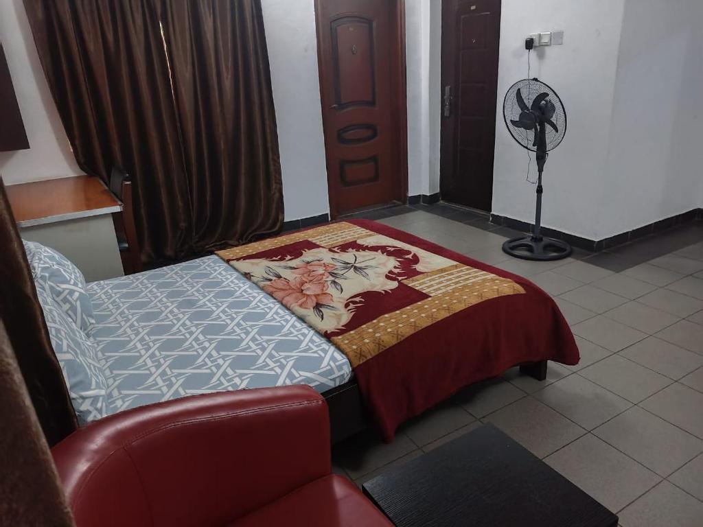 a bedroom with a bed and a chair and a fan at Engelbert Beyer Centre in Ibadan