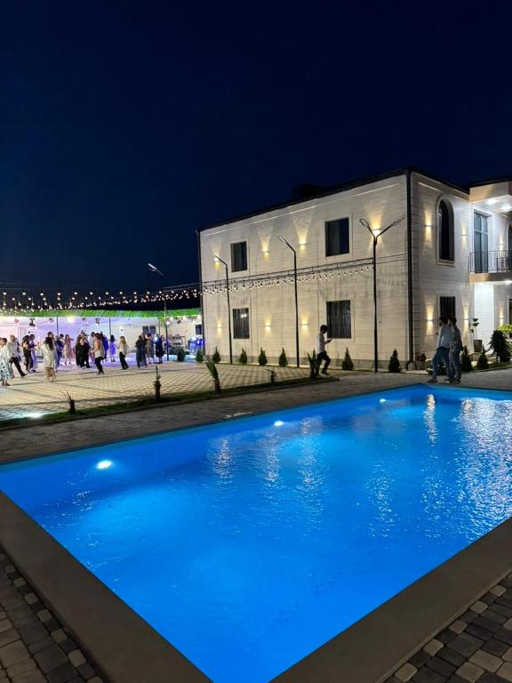 a blue swimming pool in front of a building at night at Events house With Swimming Pool in Agarak